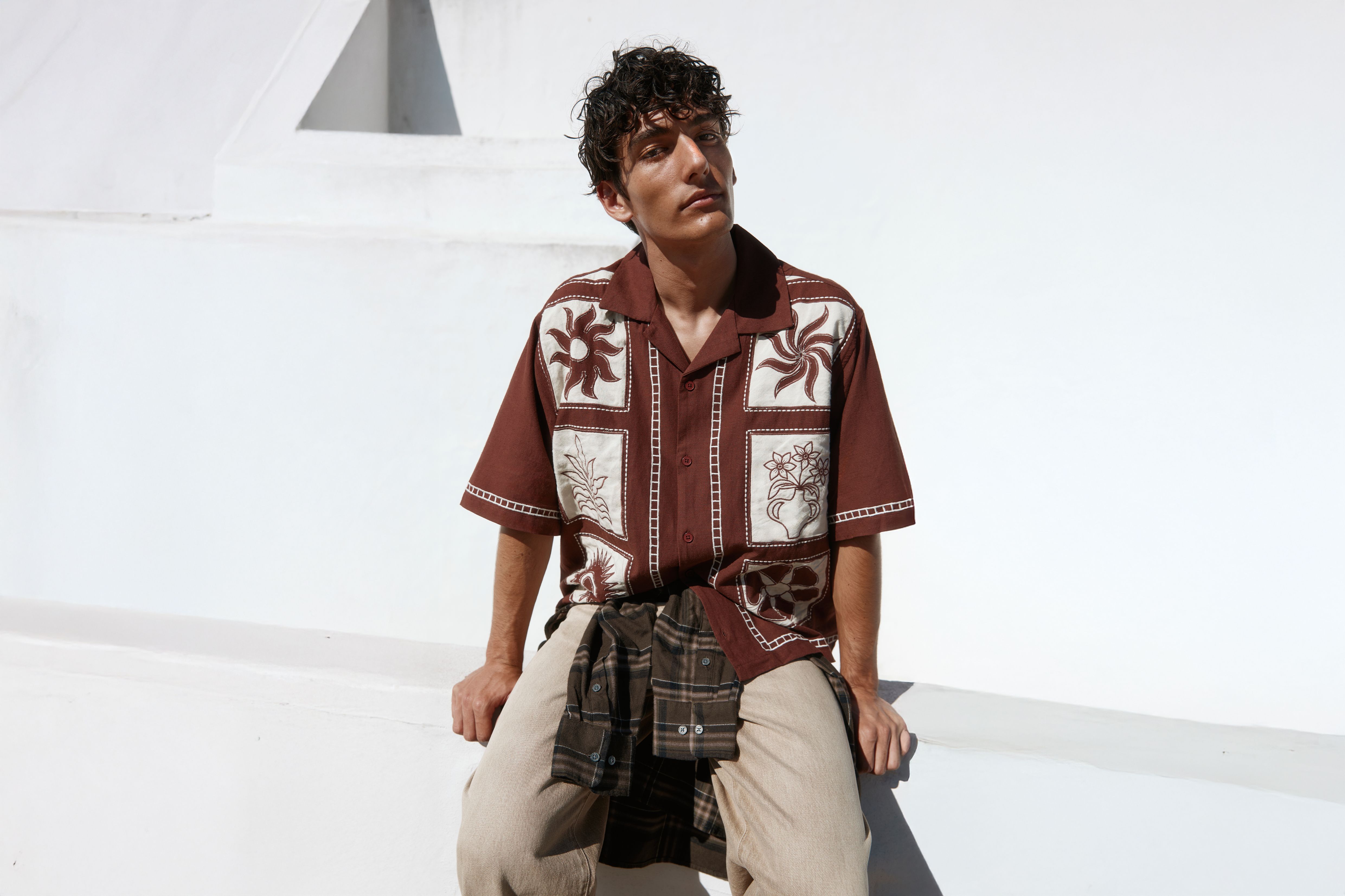 Man sitting down wearing a brown short sleeved shirt
