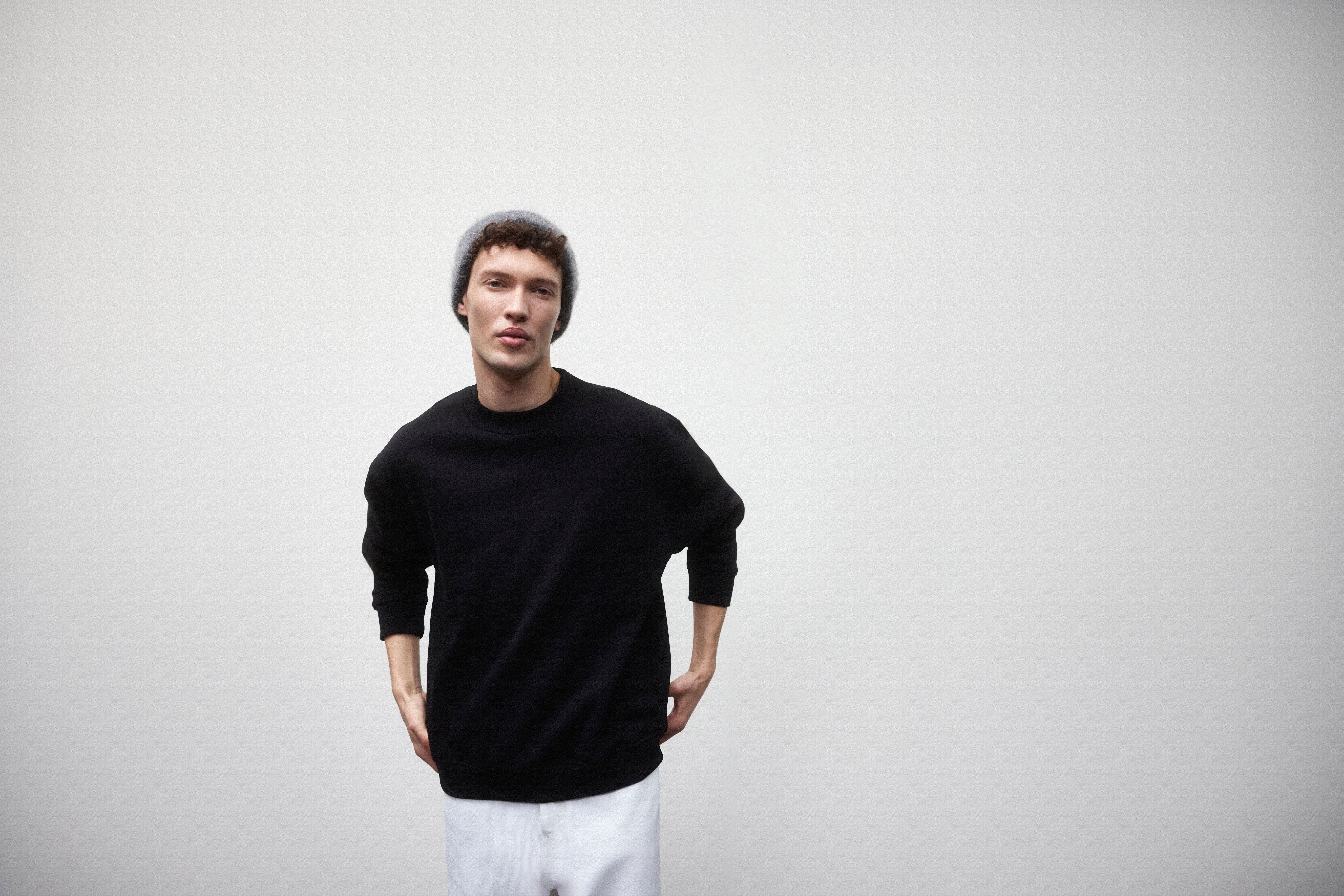 Man wearing the black sweatshirt, with white jeans and grey beanie